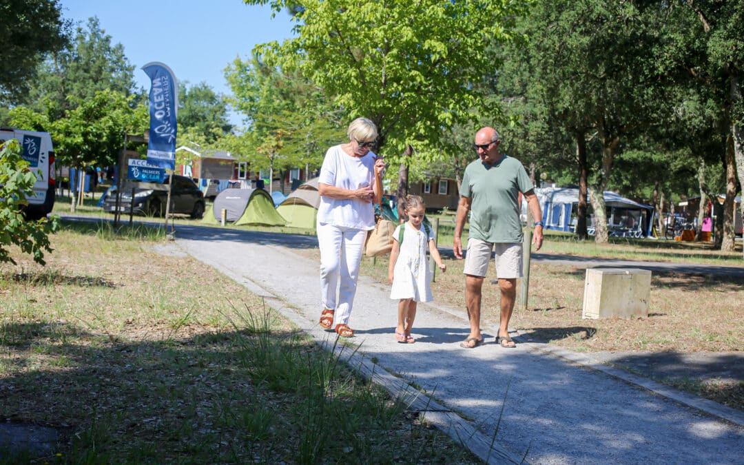 Grand-parents avec petite-fille marchant dans le camping Nature l'Airial